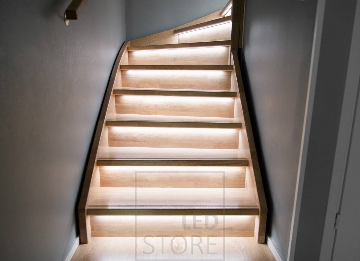 Des bandes LED sur le rebord de l'escalier éclairent les marches vers le bas avec une lumière indirecte.